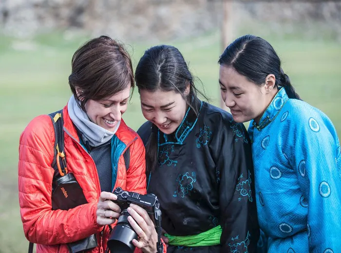 Three women are taking pictures with a camera.