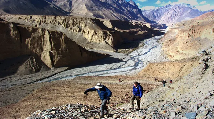 Two people hiking up a rocky path in the mountains.