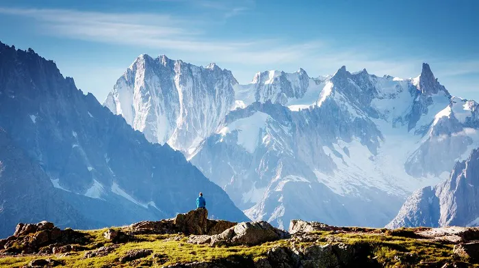 A person standing on top of a rock with mountains in the background.