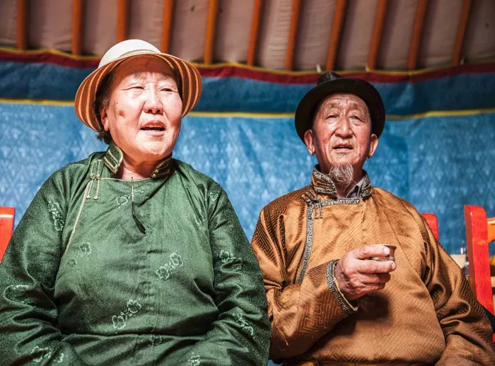 Two elderly people sitting in a yurt in mongolia.