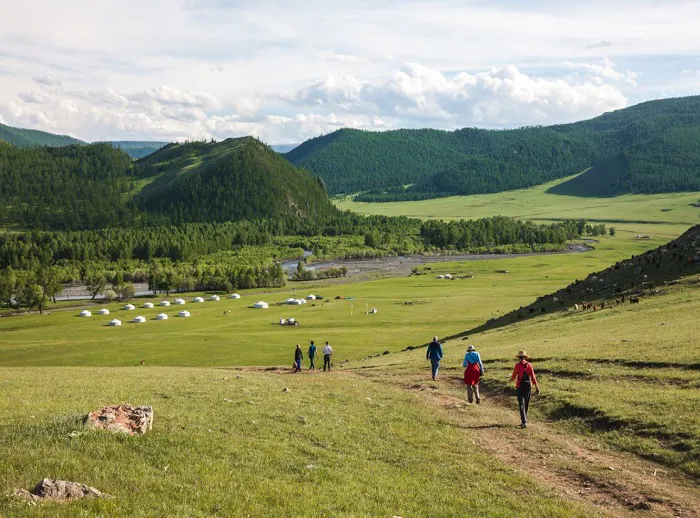 A group of people hiking through a grassy field.