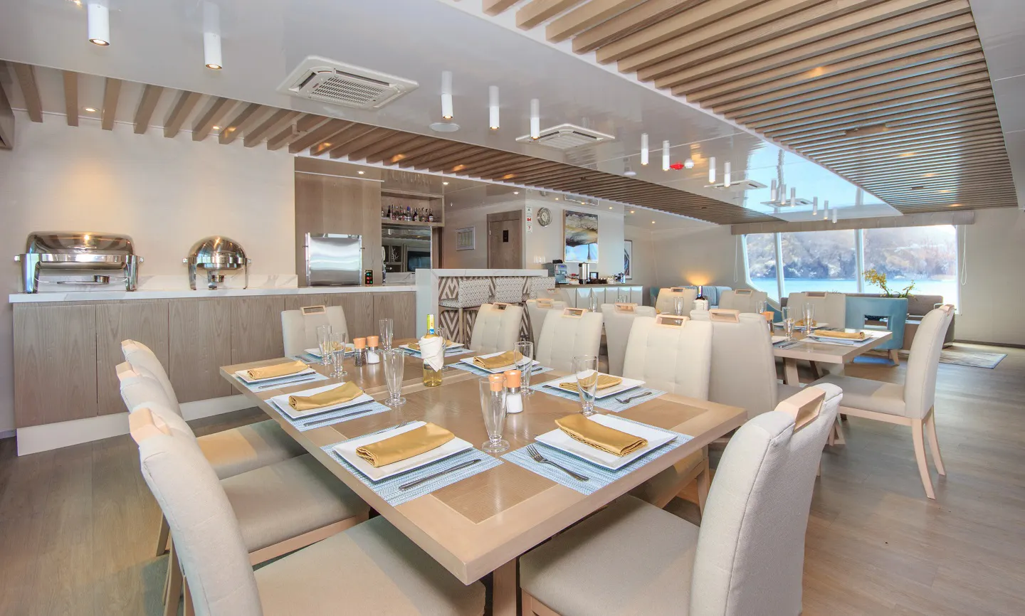 A dining room on a boat with a view of the ocean.