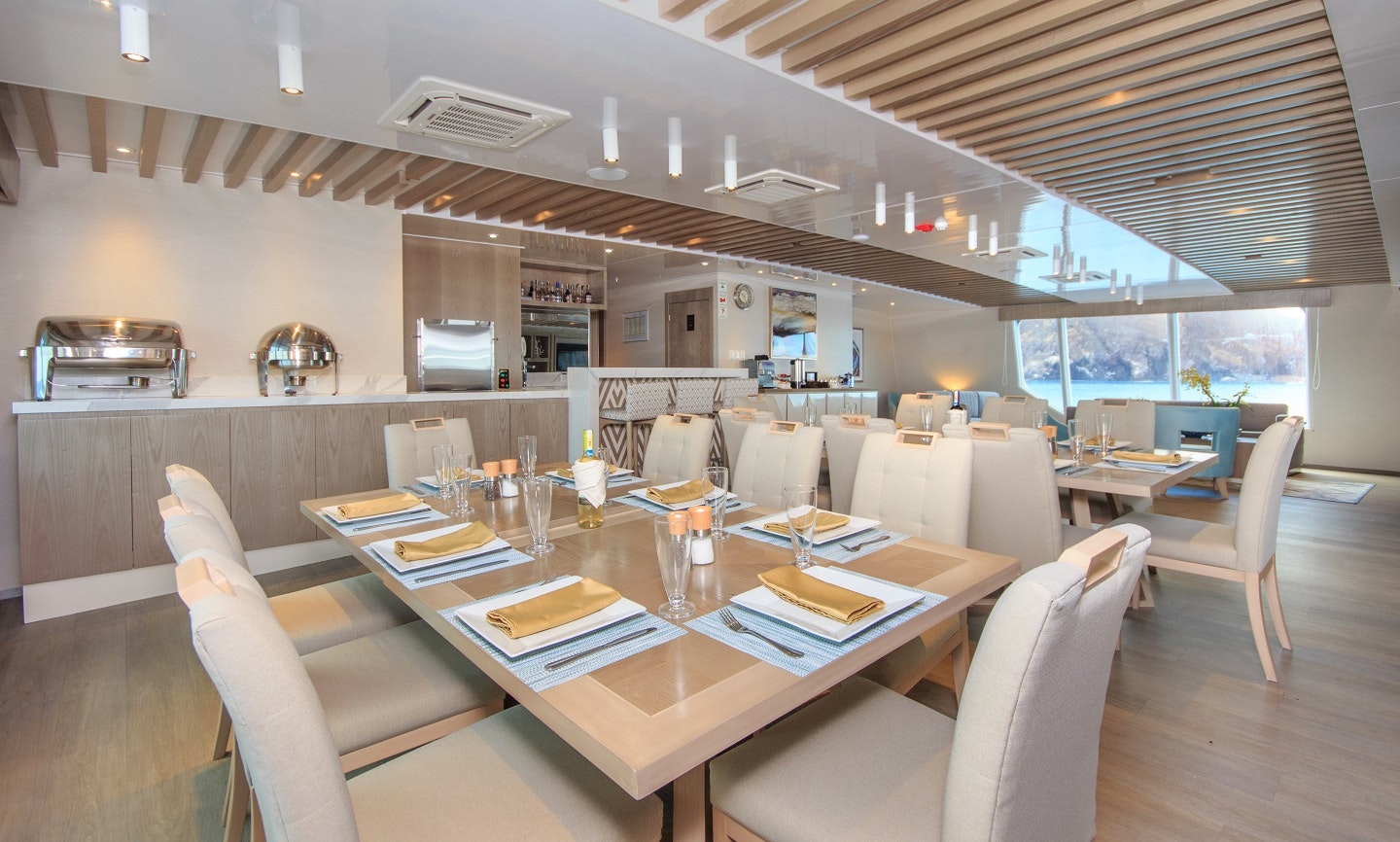 A dining room on a boat with a view of the ocean.