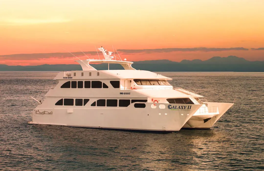 A white boat in the ocean at sunset.