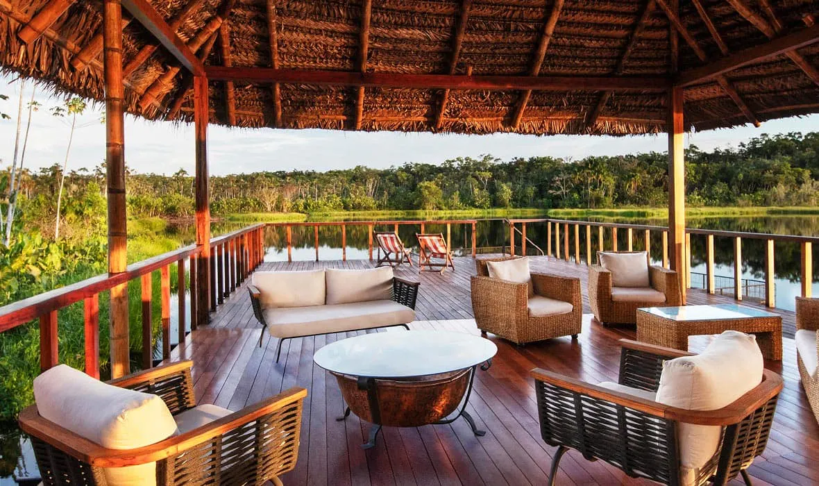 Extend your trip to Ecuador and relax on a wooden deck overlooking a lake with wicker furniture.