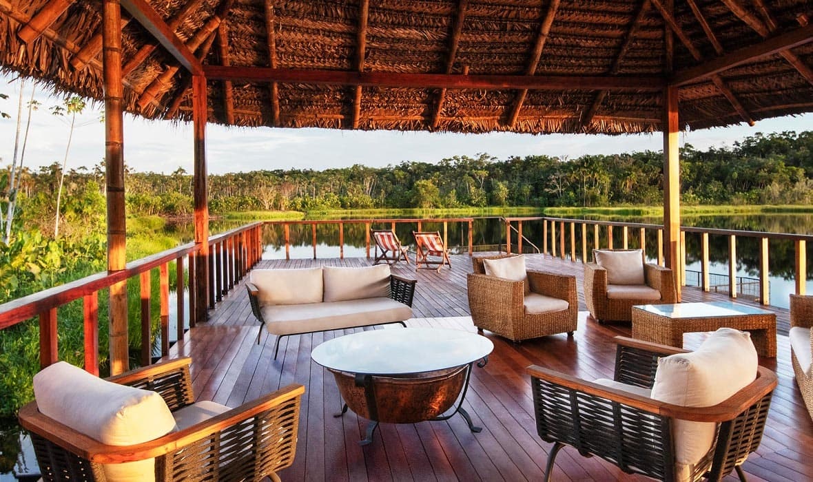 Extend your trip to Ecuador and relax on a wooden deck overlooking a lake with wicker furniture.