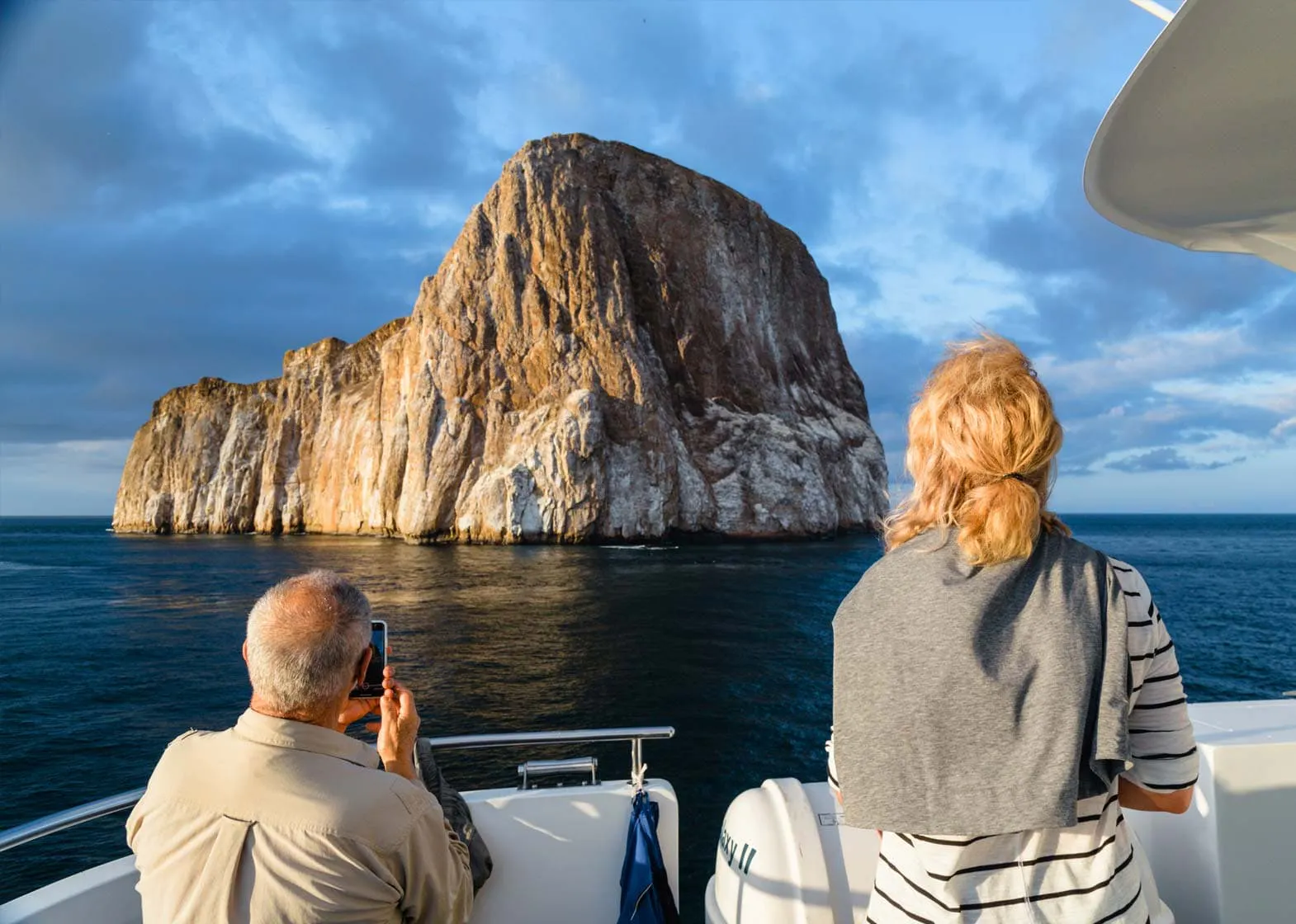 Two explorers in a boat observing a rock in the Galapagos Islands.
