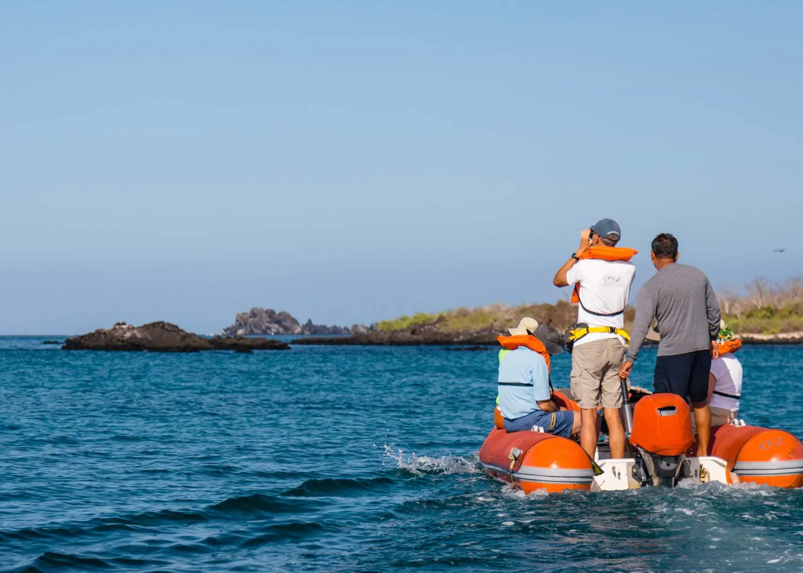 A group of people exploring the Galapagos Islands on an inflatable boat.