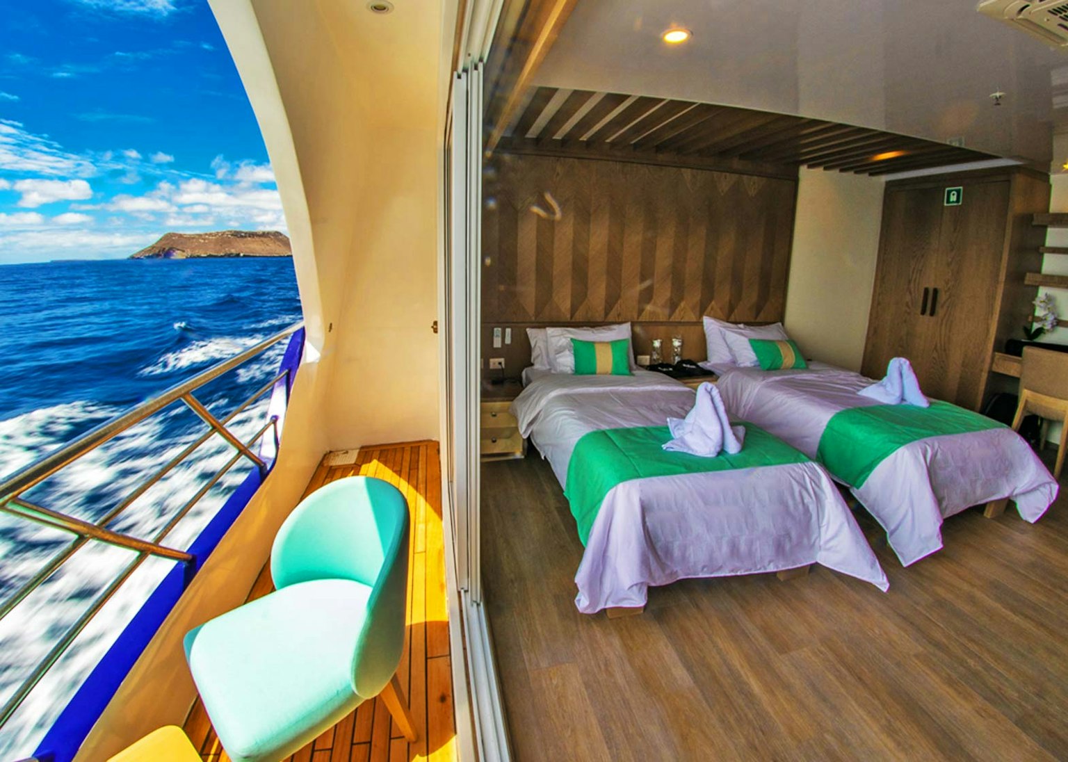 A room on a boat with two beds and a view of the ocean.