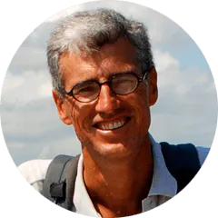 A man with glasses and a backpack smiling.