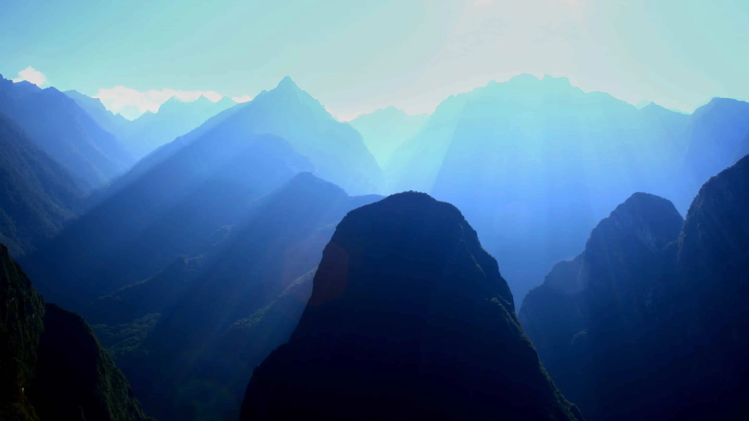 A mountain range with sun rays shining down on it.