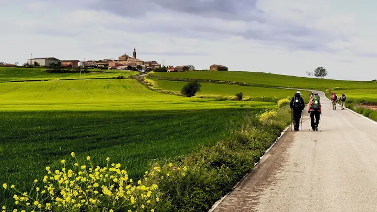 Two people enjoying one of the best hikes of a lifetime on a dirt road in a green field.