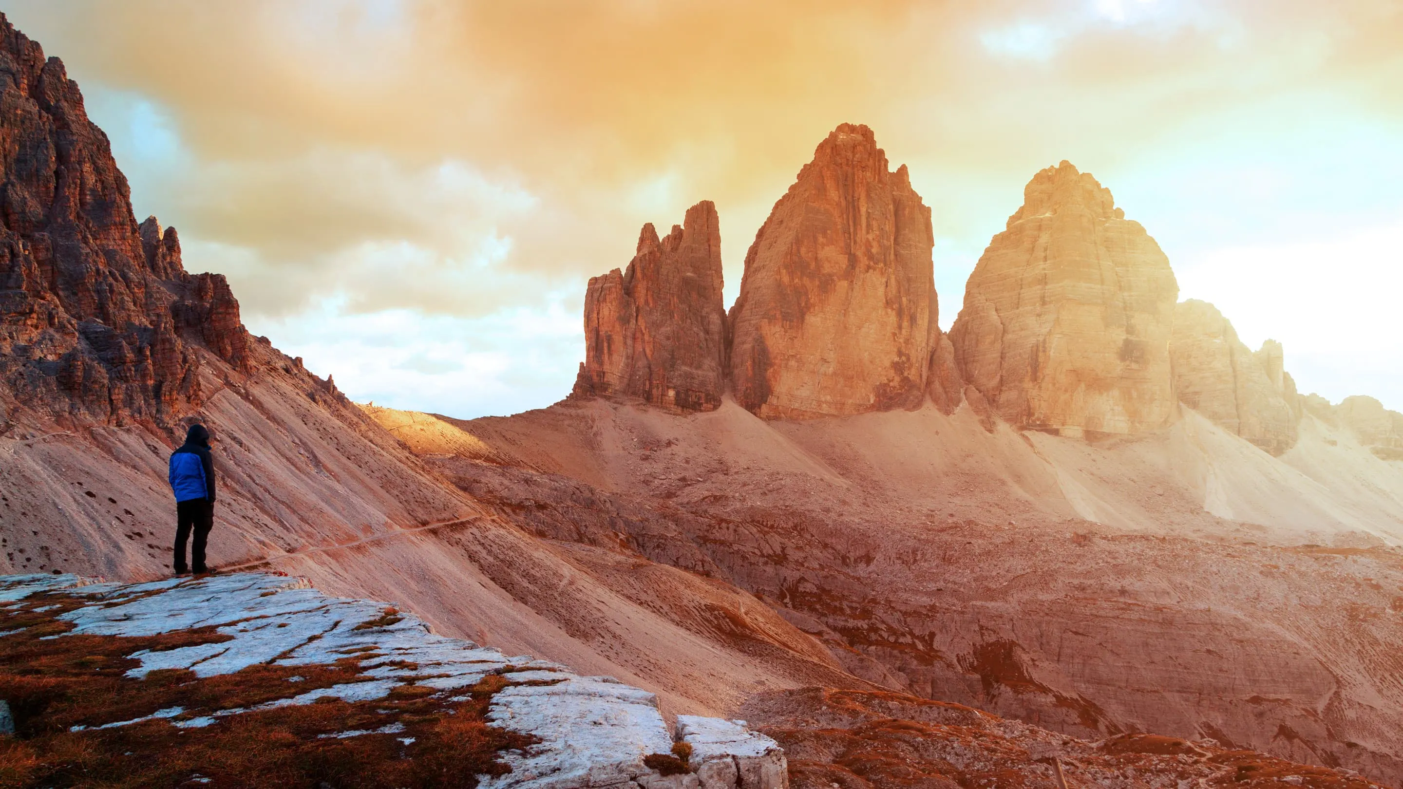 A person standing on top of a mountain overlooking a sunset.