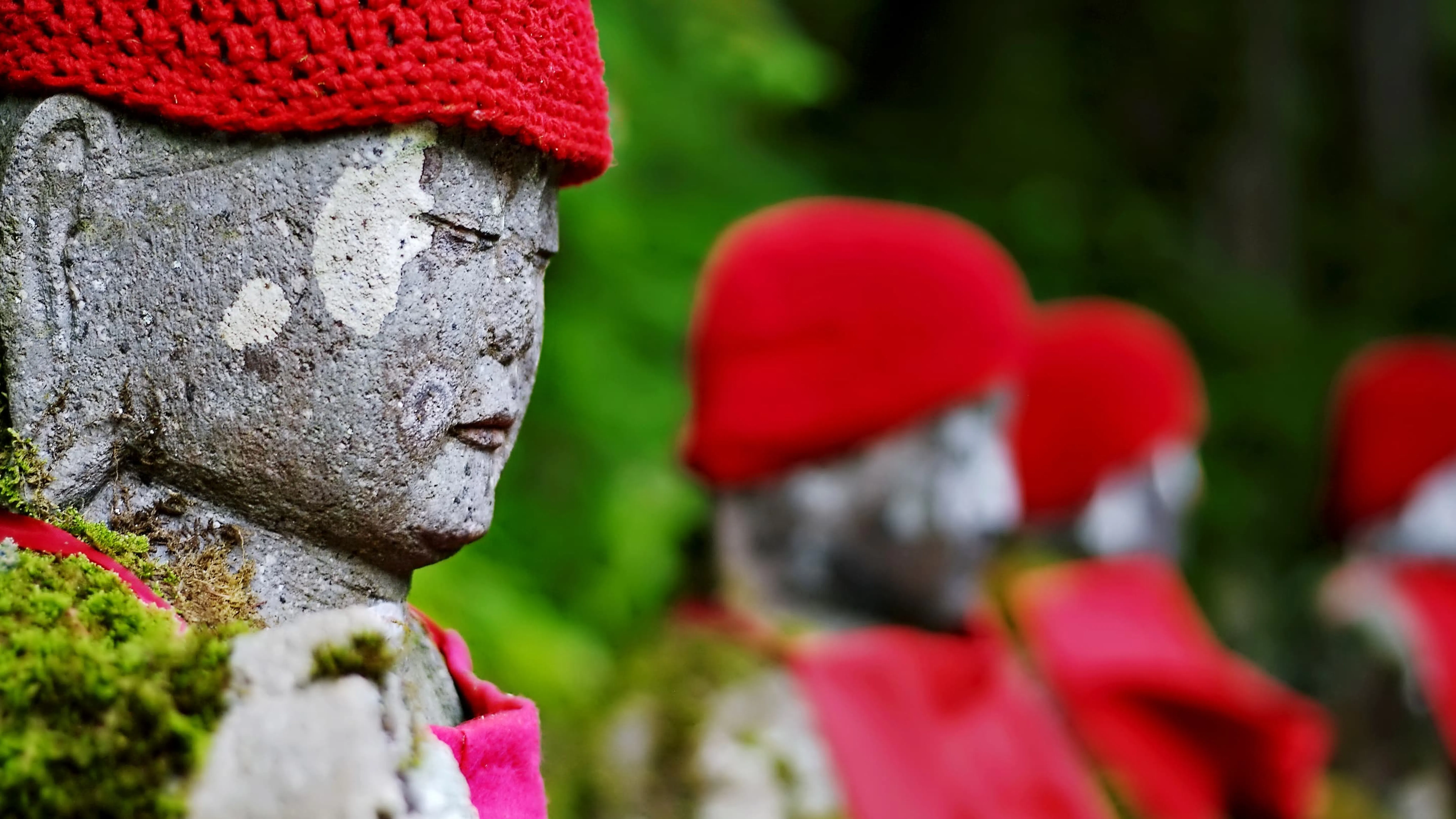 A group of buddha statues wearing red hats.
