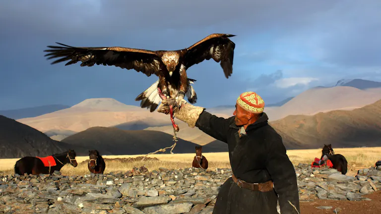 A man is holding an eagle in his hand.