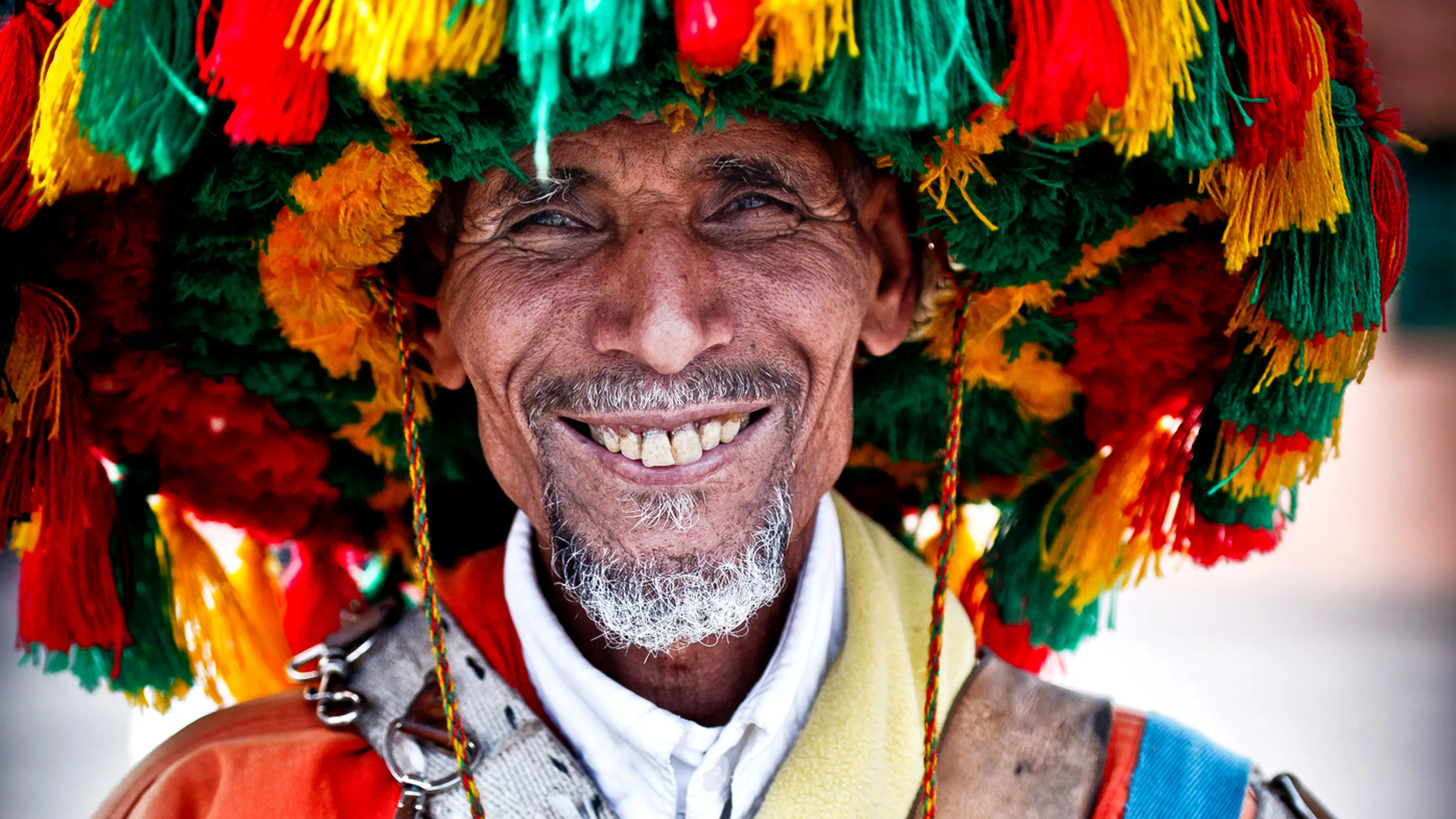 A man wearing a colorful hat is smiling.