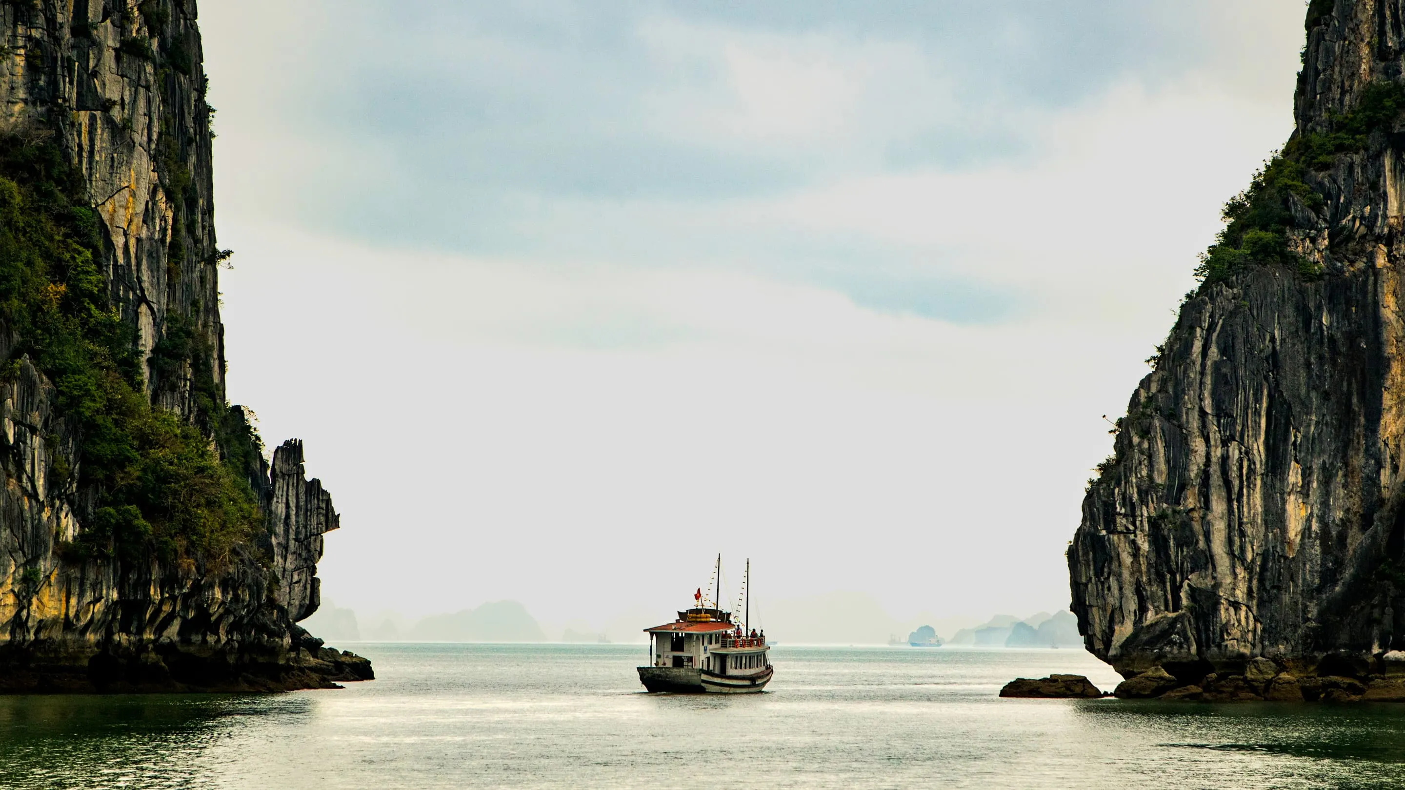 A boat is in the water near a cliff.