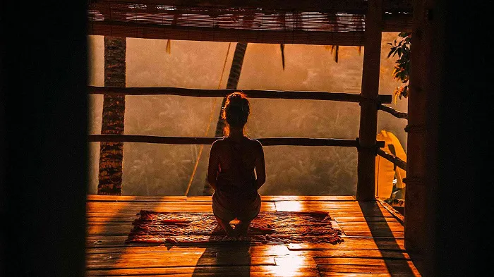 Keywords: health benefits
Description: A woman is enjoying the health benefits of sitting on a mat in front of a window.