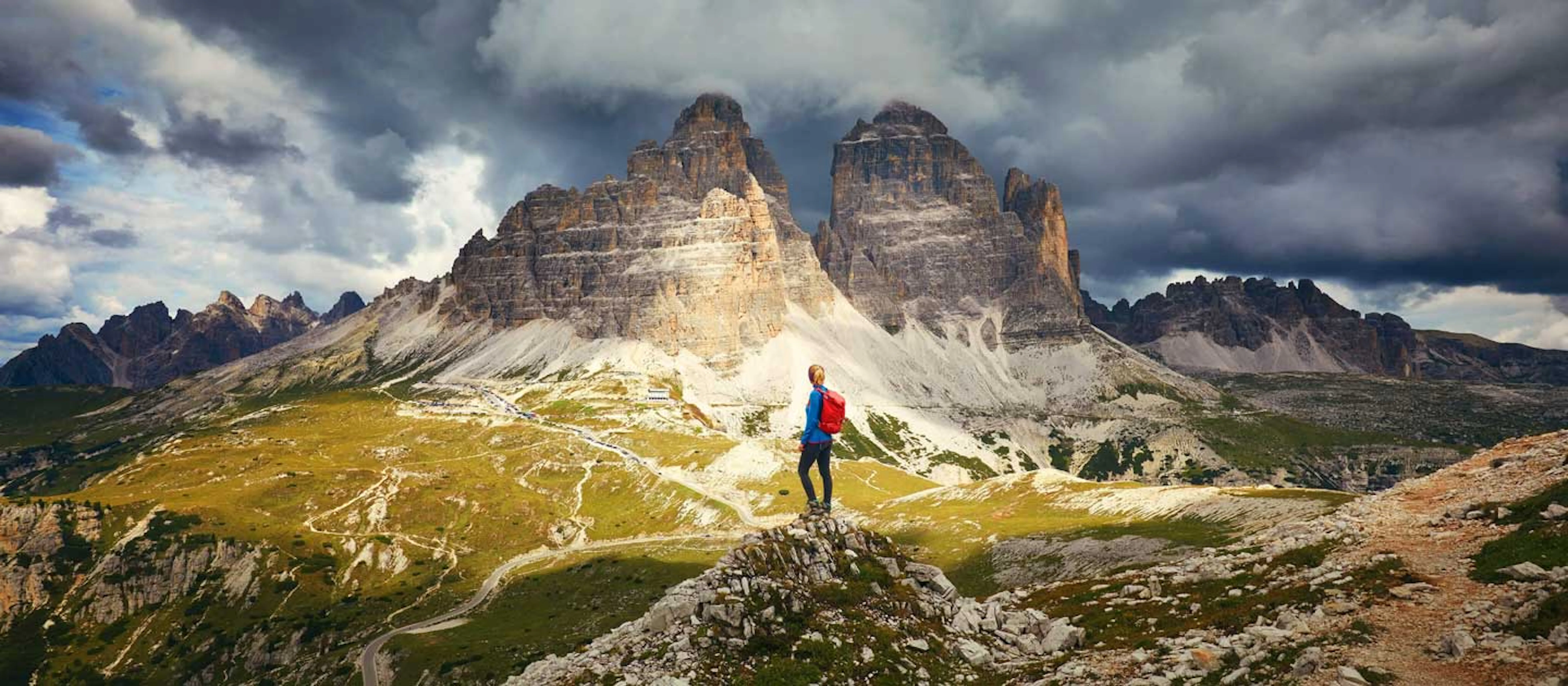 A man standing on top of a mountain in the dolomites.
