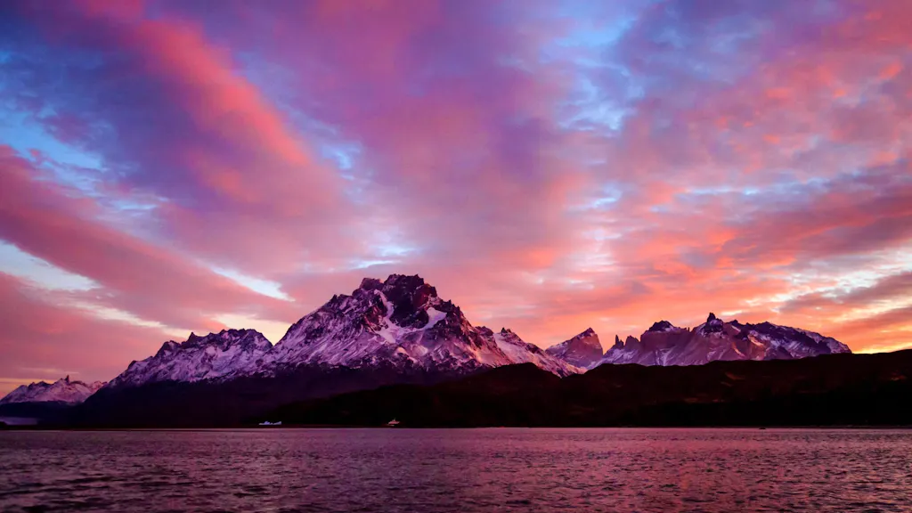 A sunset over a lake with mountains in the background.