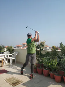 A man swinging a golf club on a rooftop.