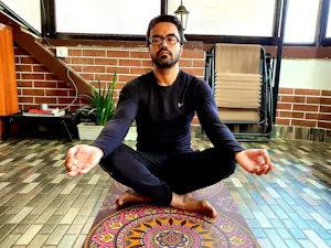 A man meditating on a yoga mat.