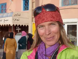 A woman wearing a hat and sunglasses in front of a building.