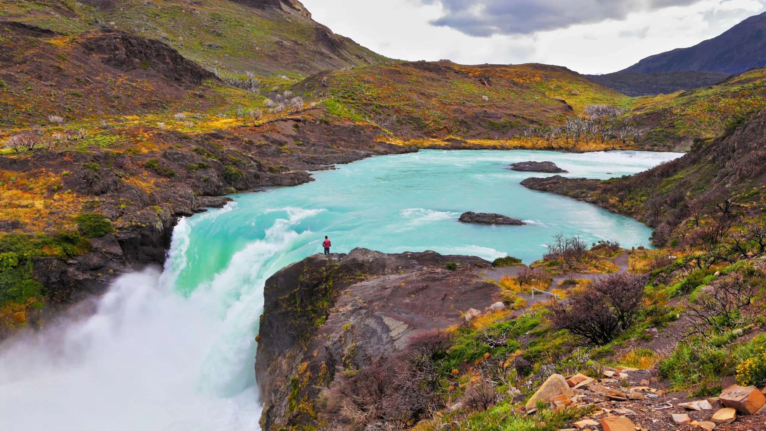 A person is standing on the edge of a waterfall.