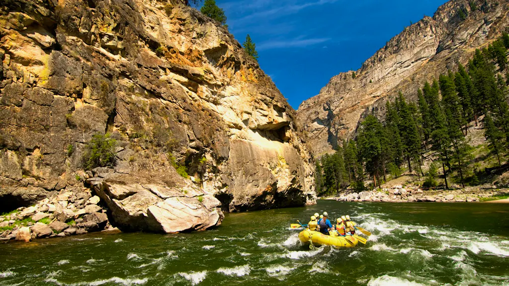 A group of people rafting down a river in a canyon.