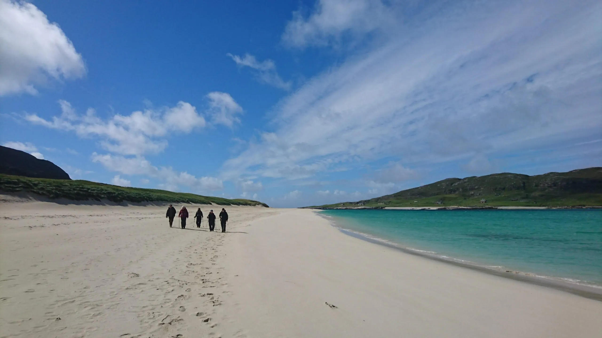 A group of people walking on a sandy beach.