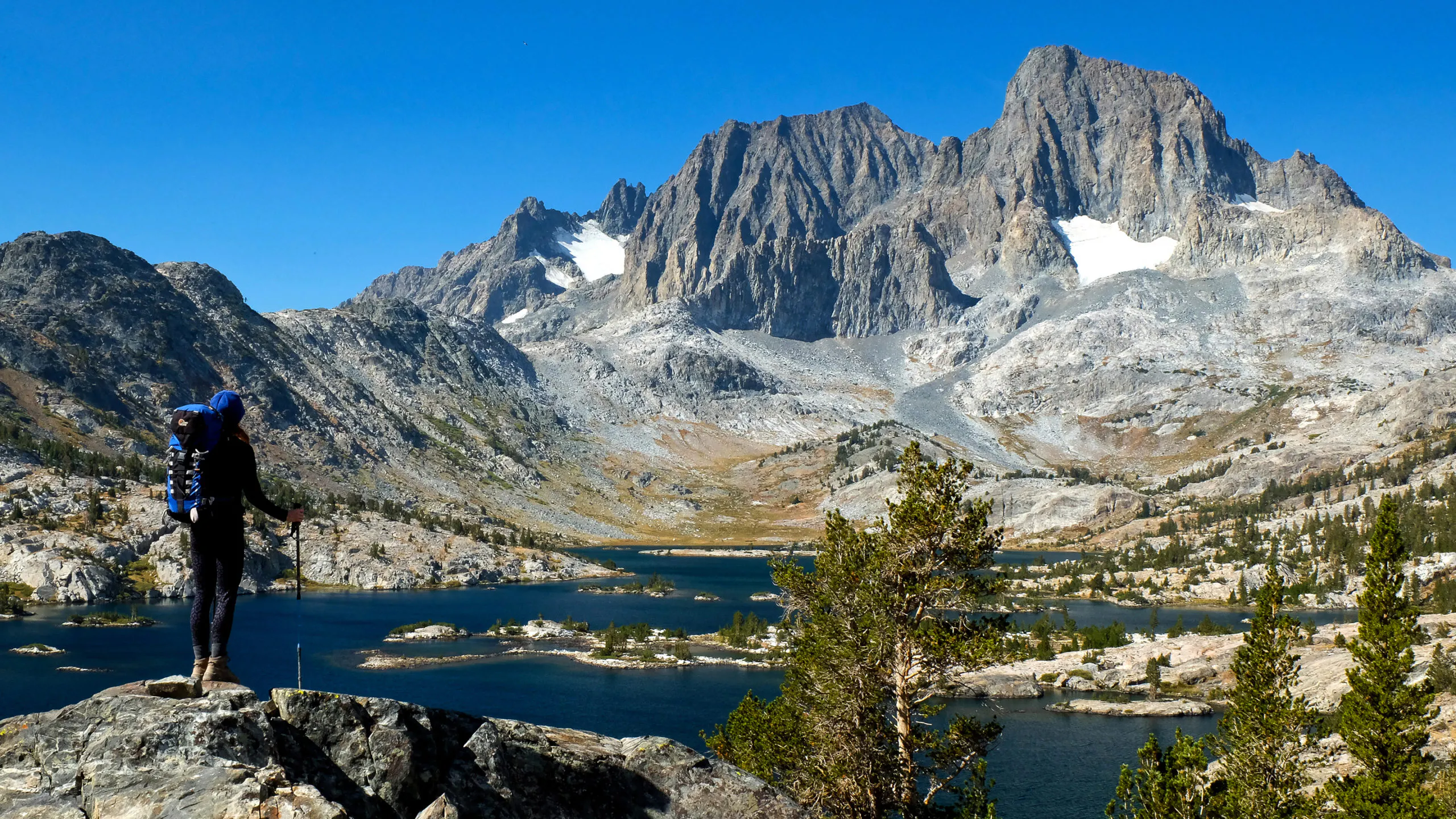 A hiker standing on top of a mountain overlooking a lake.