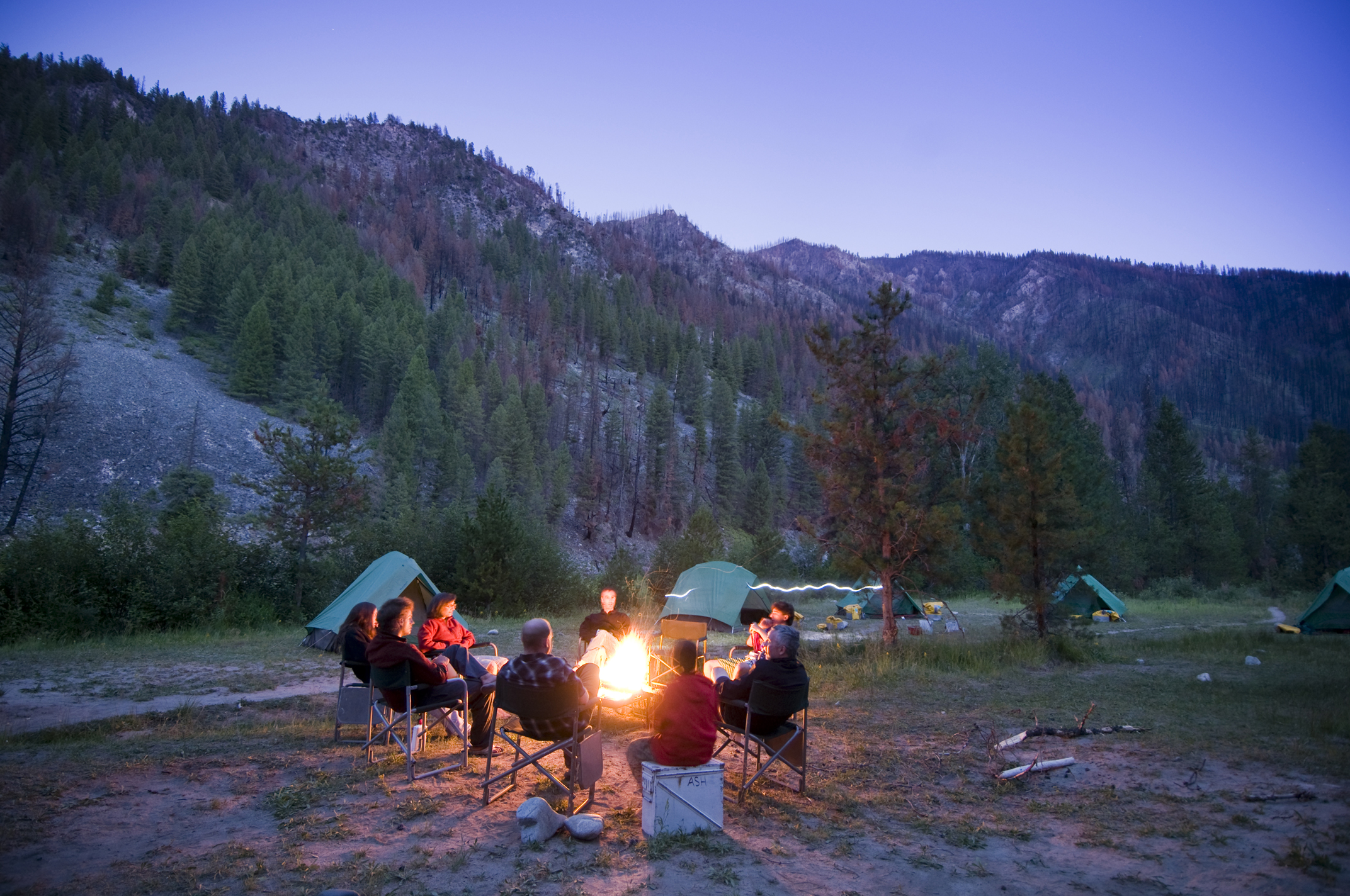 A group of people enjoying adventure travel around a campfire.