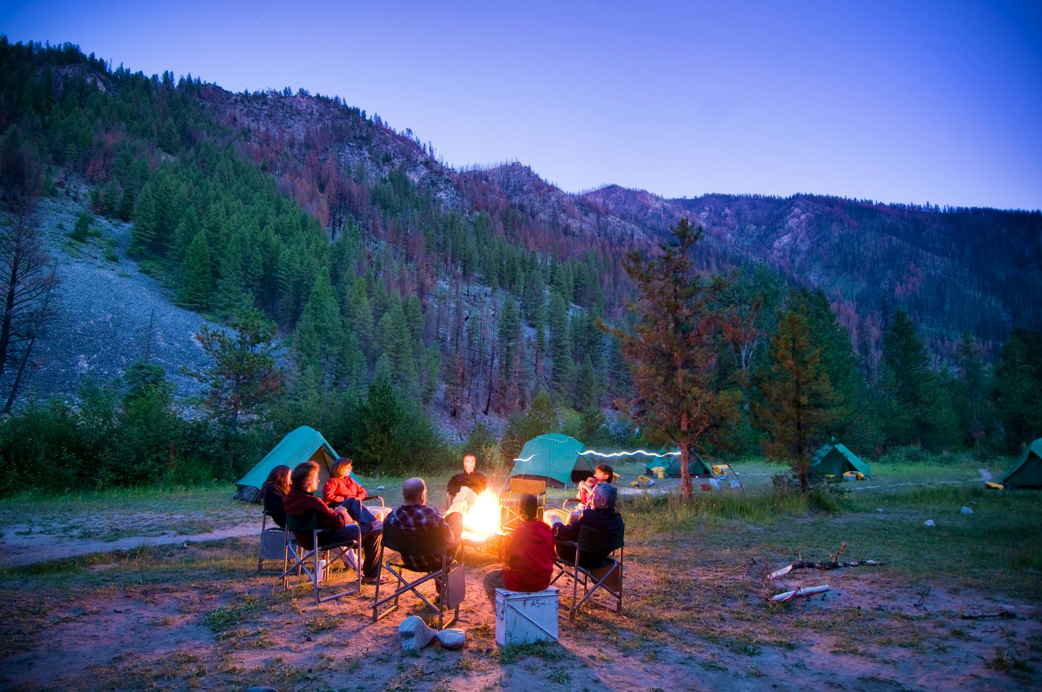 A group of people enjoying adventure travel around a campfire.