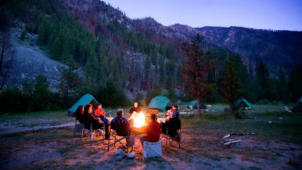 A group of people enjoying an Adventure Travel experience around a campfire in the mountains.