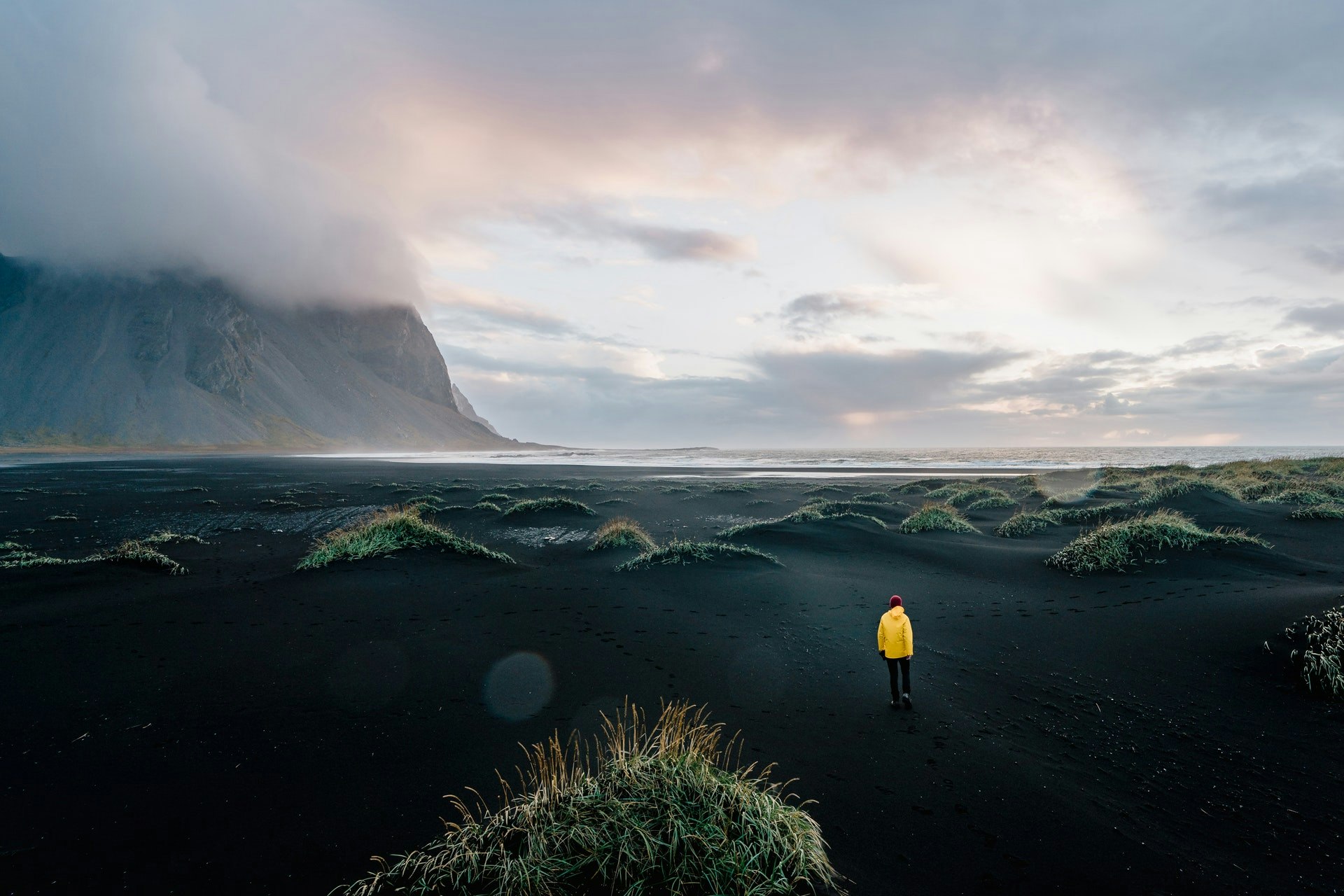 A person enjoying adventure travel on a black sand beach with a mountain in the background.