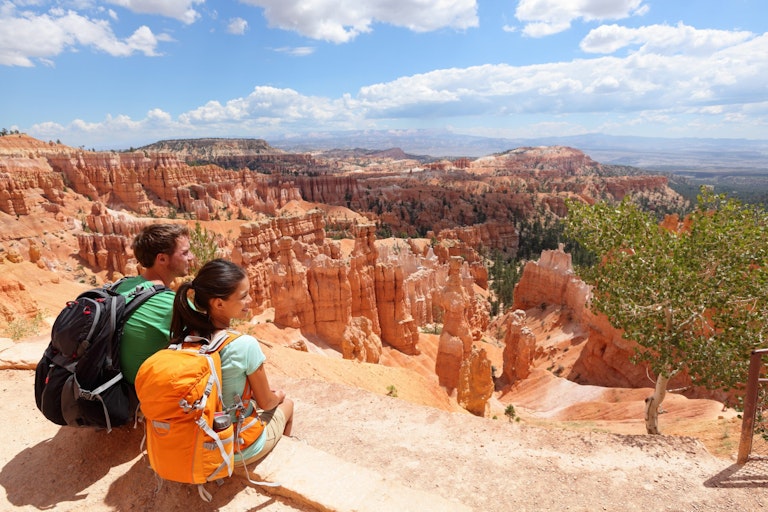 A female and a male sitting on the cliff of a mountain in Utah
