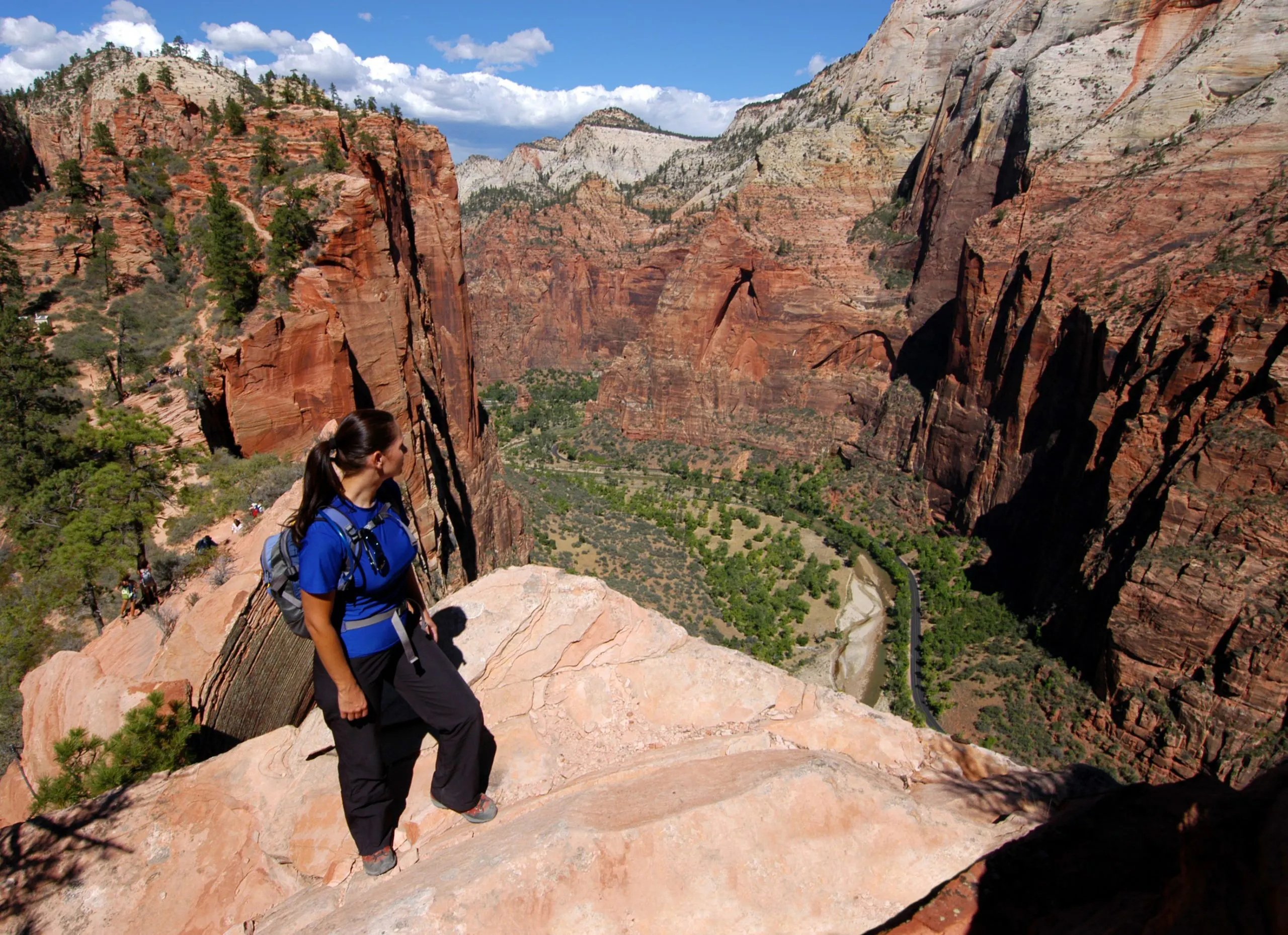 A woman standing on a rocky cliff overlooking a canyon in Utah national parks.
