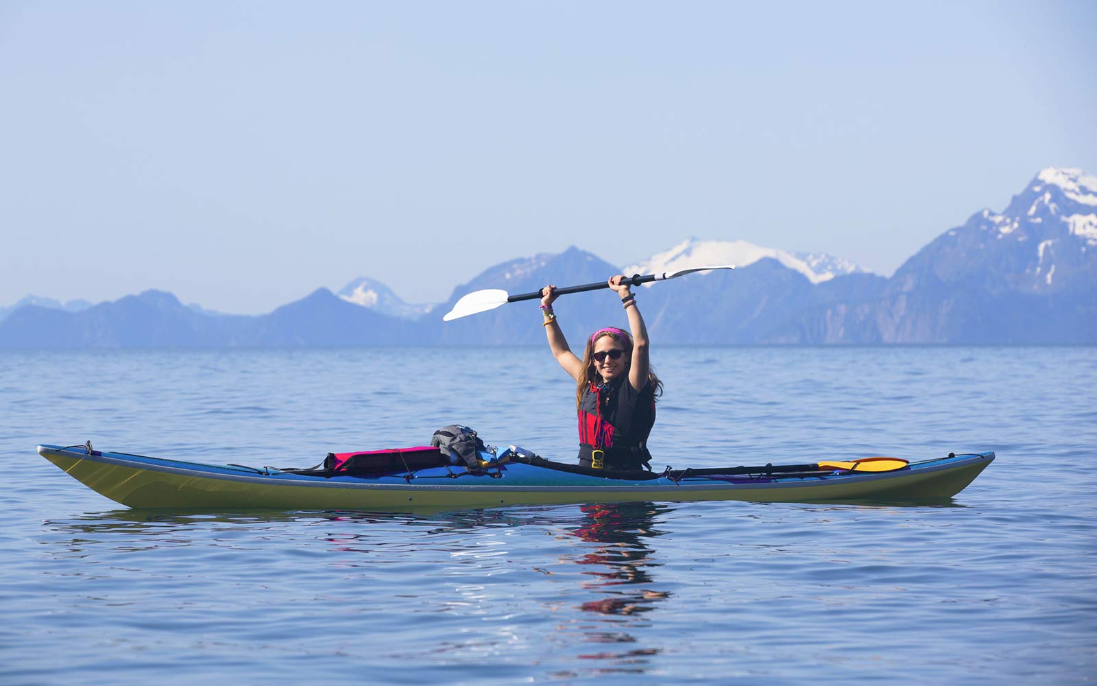 A woman in a kayak with mountains in the background.