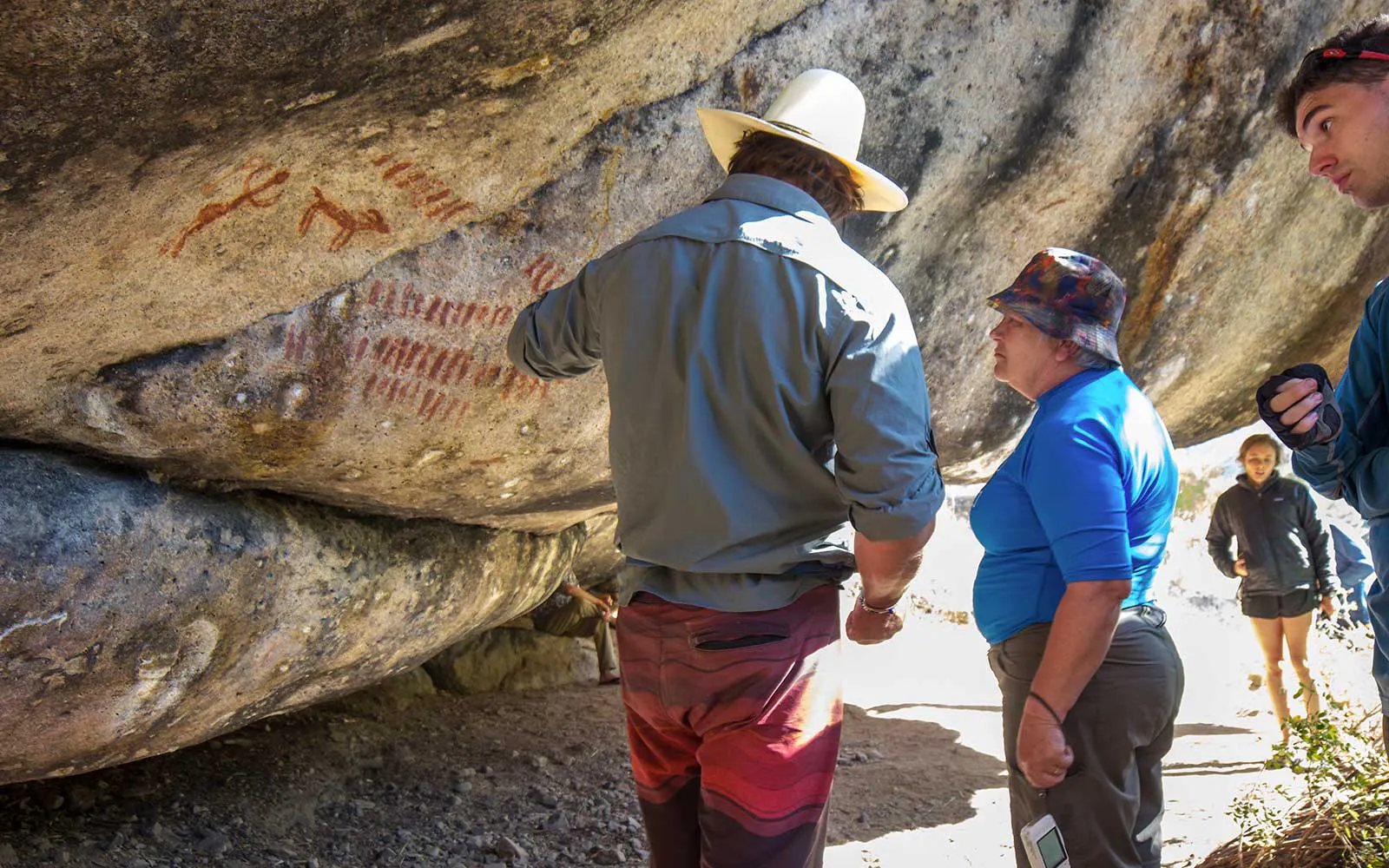 A group of people standing next to a large rock with writing on it.