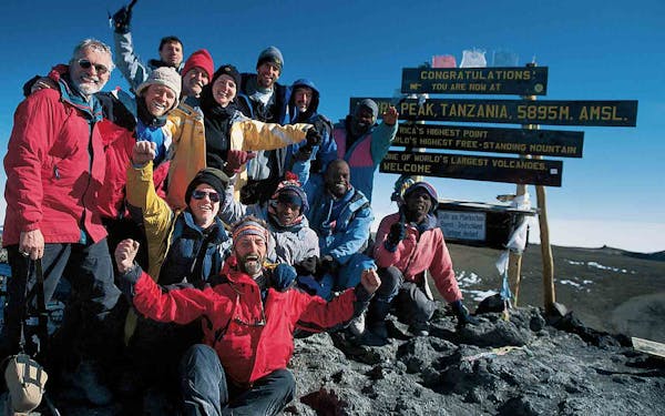 A group of people posing for a picture on top of a mountain.