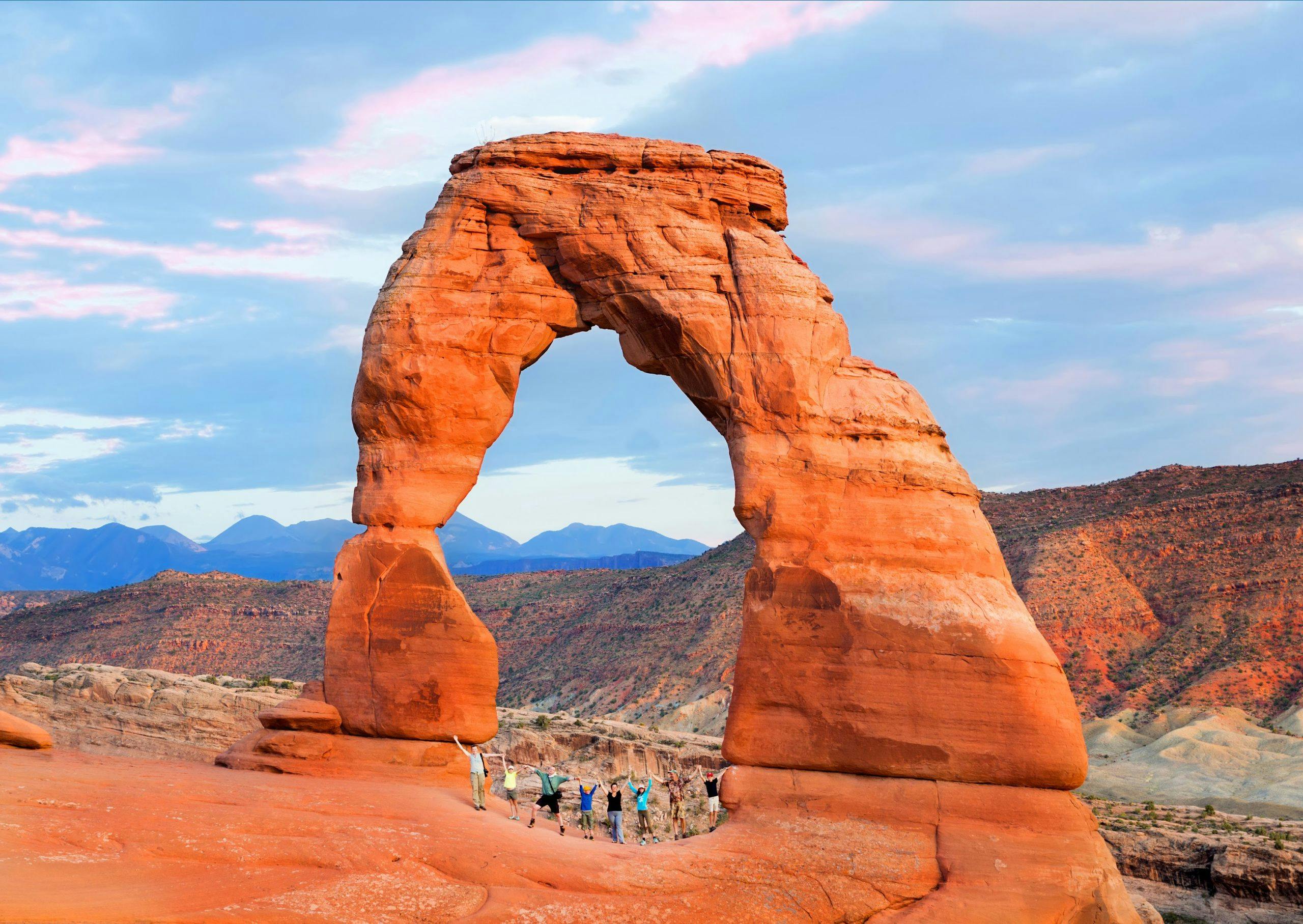 A group of people (two families with children) joined hands and raised them. Arches National Park, Utah.
