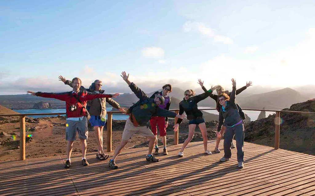 A group of people standing on a wooden deck with their arms raised.