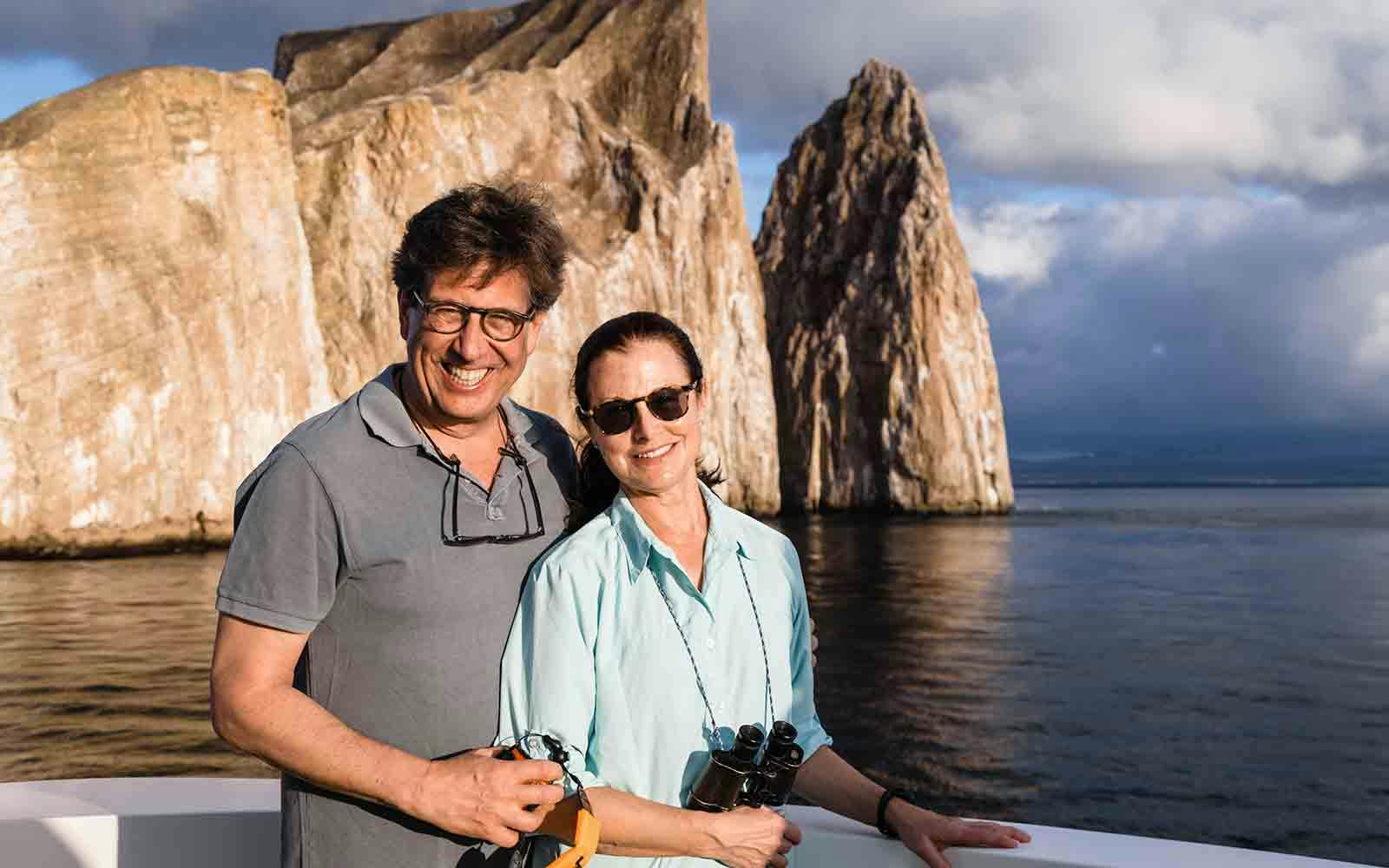A man and woman posing for a photo on a boat in the galapagos islands.