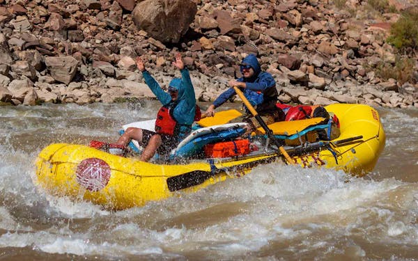 Two people rafting down a river in a yellow raft.