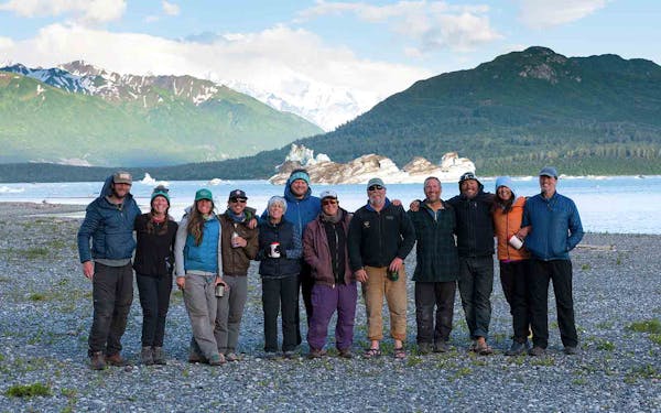A group of people standing in front of a glacier.