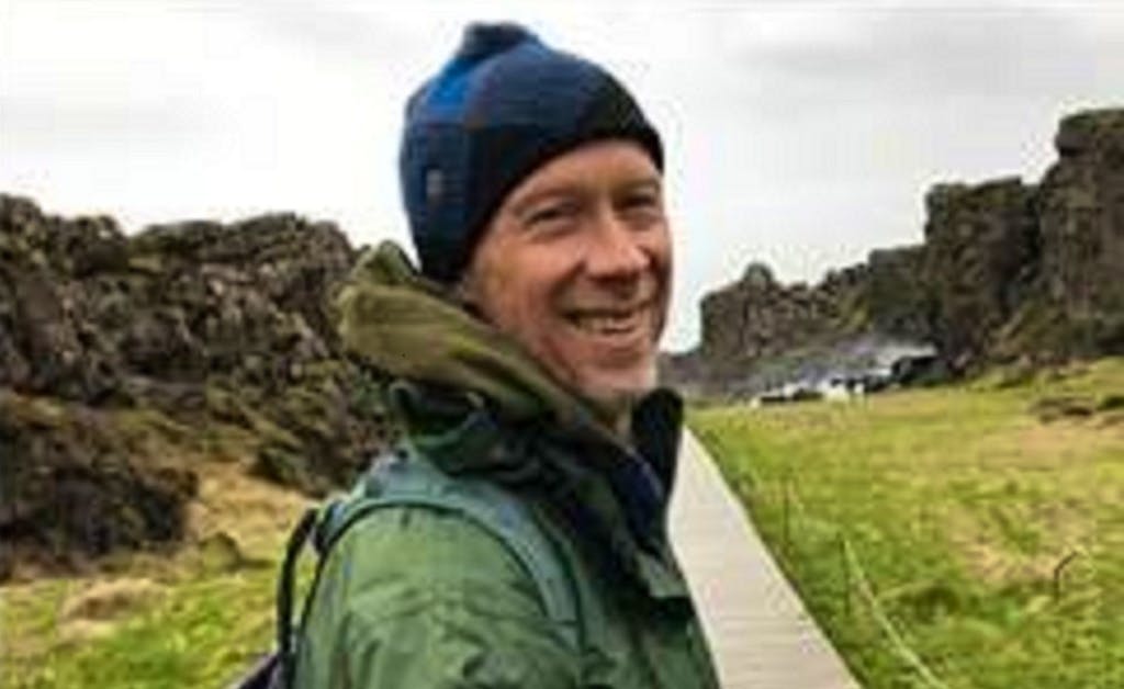 A man wearing a hat and jacket on a path in iceland.