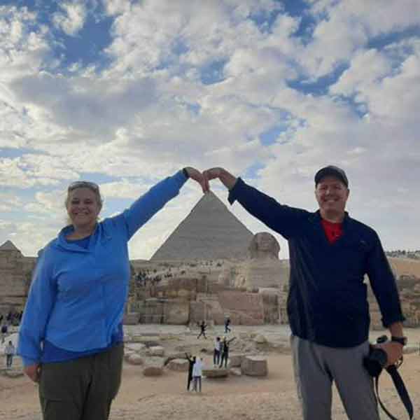Two people posing in front of the pyramids of giza.