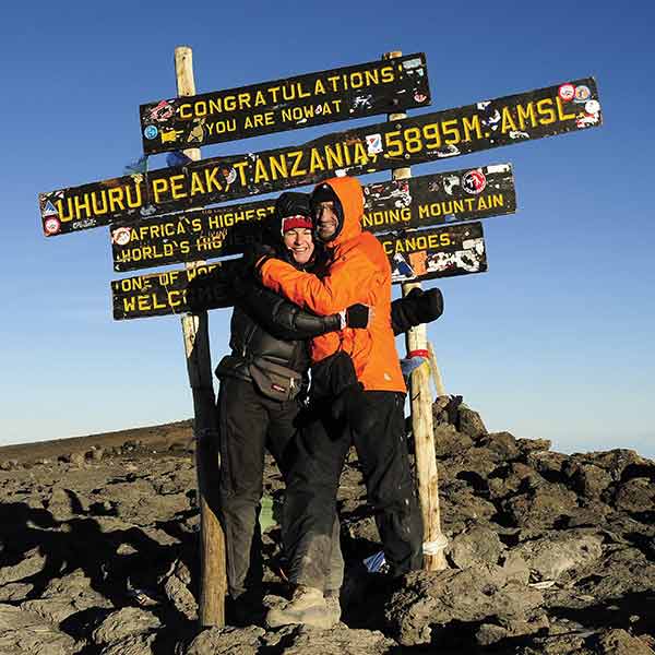 Two people hugging at the summit of mt kilimanjaro.