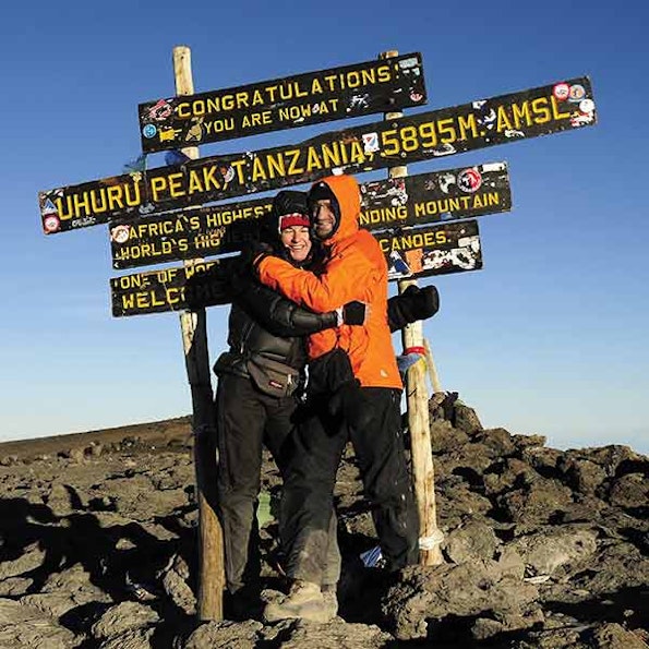 Two people hugging at the summit of mt kilimanjaro.