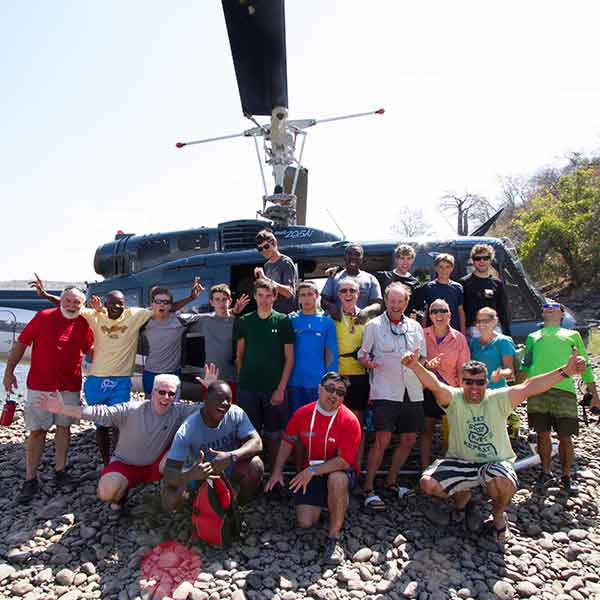 A group of people posing in front of a helicopter.